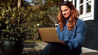 Pige med computer ude i haven