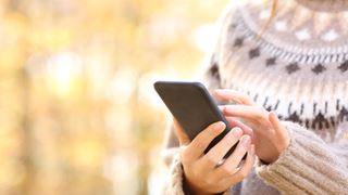 Dame i sweather med mobiltelefon i hånden