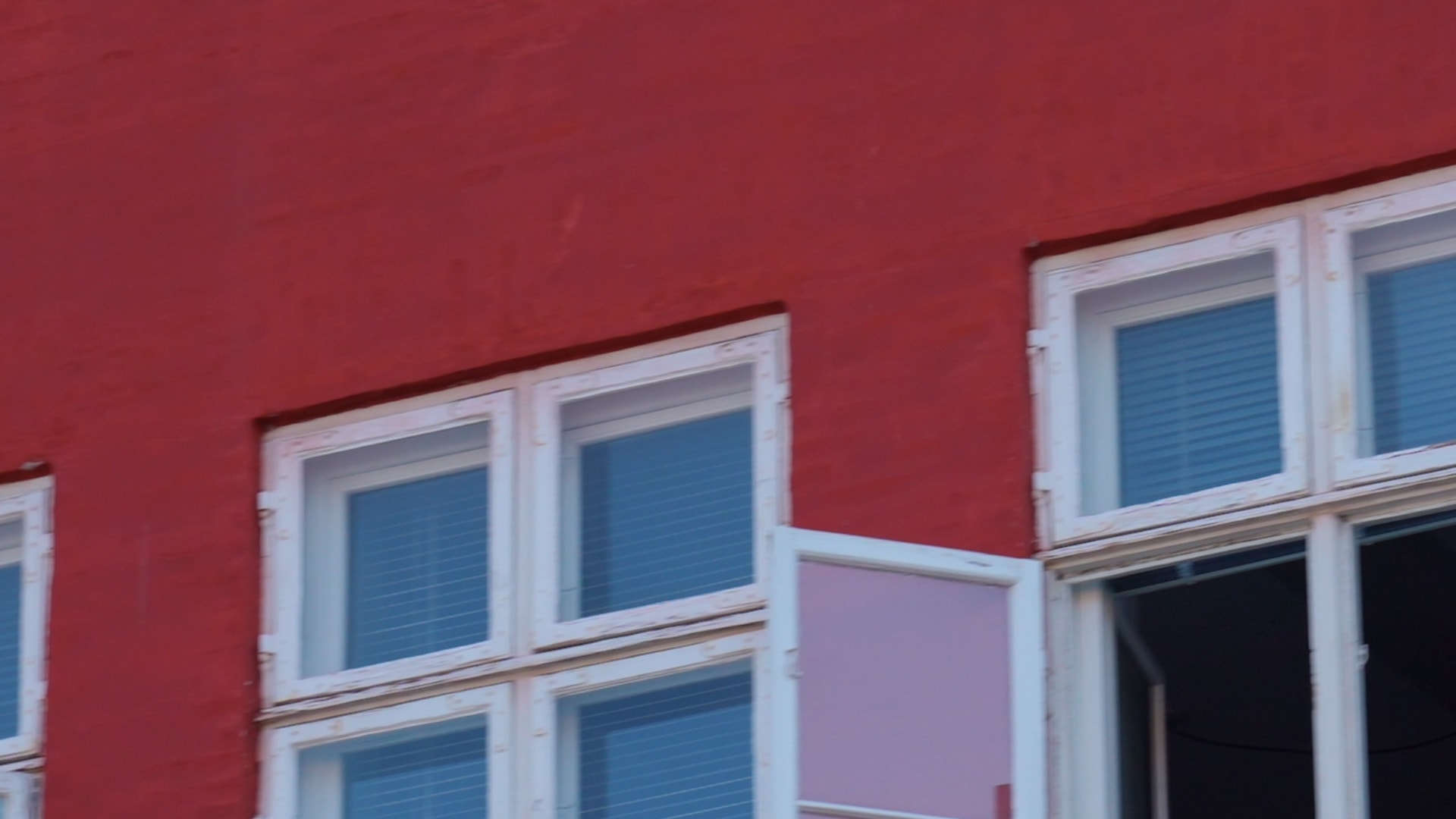 Nærbillede af vinduer i en rødmalet lejlighedsbygning