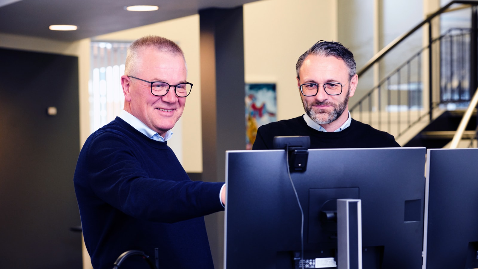 Puljeafkast 2025 To medarbejdere i Sparekassen Thy kigger på en computerskaerm